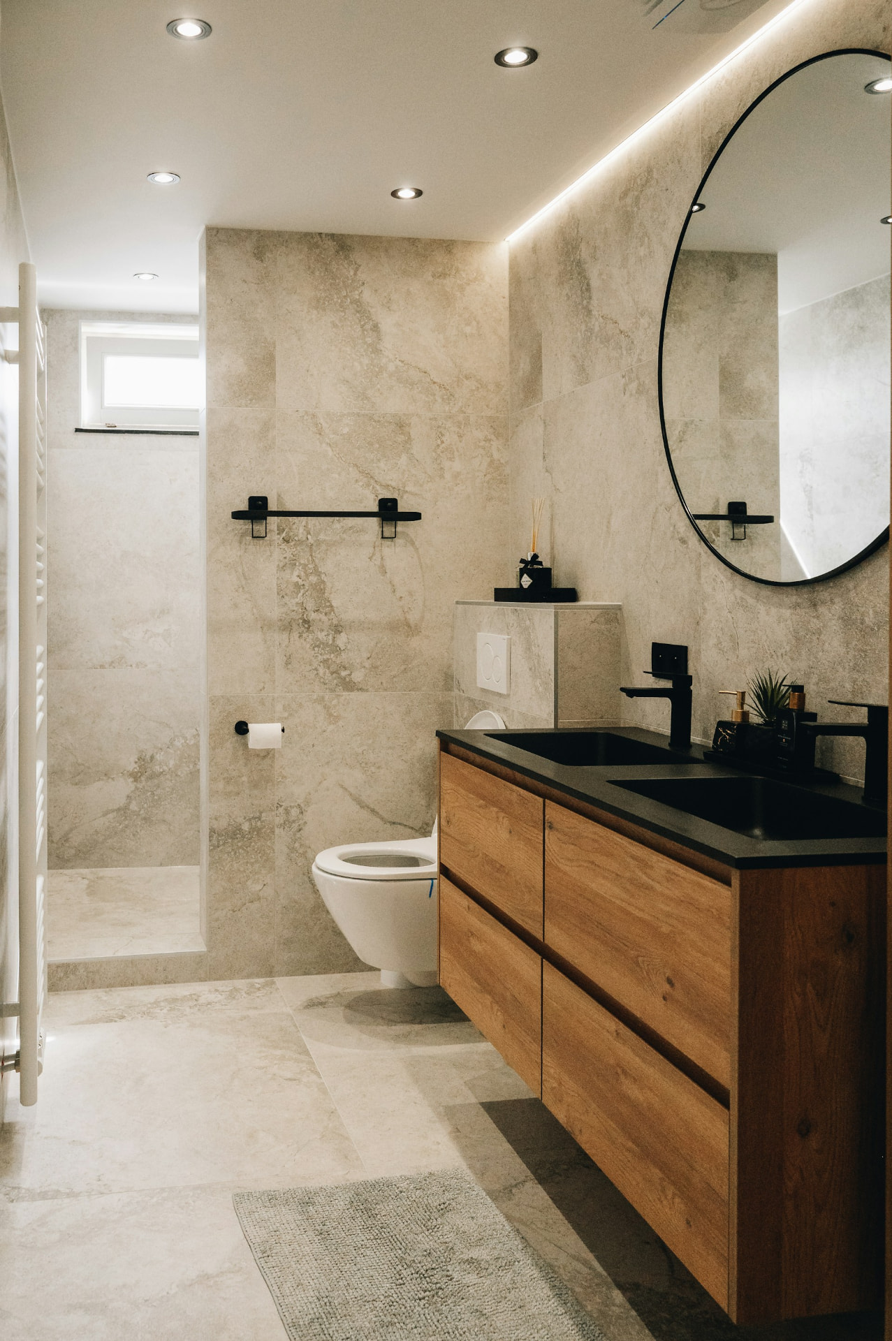 A freshly cleaned modern bathroom with a wood vanity and round mirror